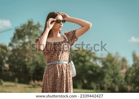 A young beautiful girl in the park on a summer day looks into the distance.