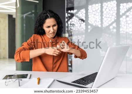 Female office worker overtired has severe pain in fingers and joints, Hispanic woman overworked at workplace with laptop at work. Royalty-Free Stock Photo #2339453457