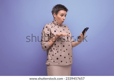 indignant 30 year old european woman with dyed gray short hair in a skirt and blouse looks at the screen of the phone