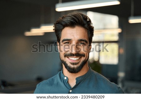 Smiling handsome young business man looking at camera in office, headshot close up corporate portrait. Happy Latin businessman, male entrepreneur, professional manager or company employee at work. Royalty-Free Stock Photo #2339480209