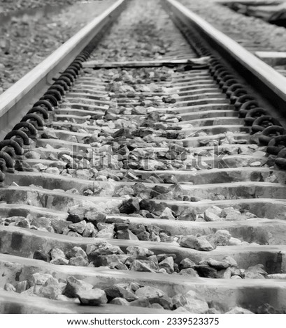 a photography of a train track with rocks and gravel on the tracks, a black and white photo of a train track with rocks on it.