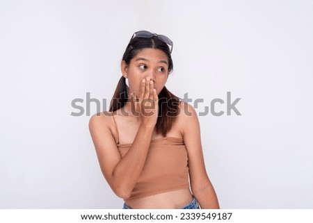 A young asian woman shows surprise after hearing shocking gossip. Isolated on a white background. Royalty-Free Stock Photo #2339549187
