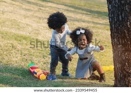 African boy helps little sister to get up from falling and comfort her, girl crying loudly, play outdoor in summer Royalty-Free Stock Photo #2339549455
