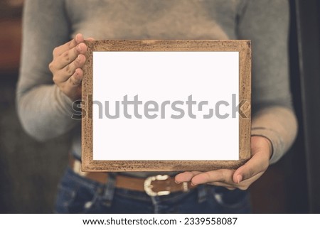 woman holding blank wooden frame in coffee shop