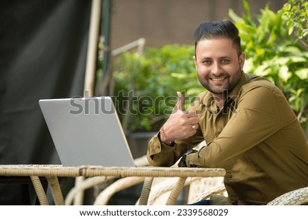 Indian man showing thump up while using laptop Royalty-Free Stock Photo #2339568029