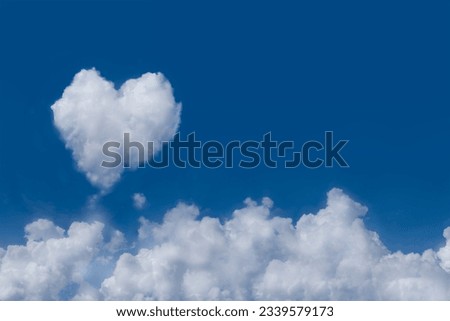 Group of white fluffy clouds on fresh blue sky with one softy cloud shaping like a heart. Background with copy space for lovely content or meteorology presentation or natural and environment concept. Royalty-Free Stock Photo #2339579173