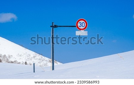 Road sign half buried under deep snow (Niseko, Hokkaido, Japan)