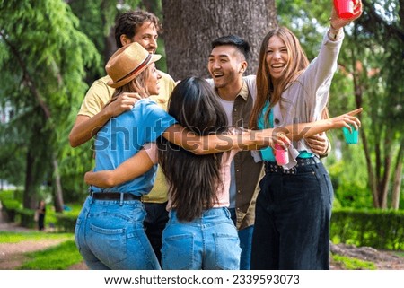 Multiethnic group of birthday party in the city park hugging in a symbol of friendship forever and smiling a lot