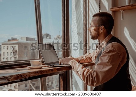 Man with glasses by the window working at a computer on a sunny day. High quality photo