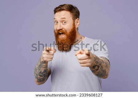 Young redhead bearded man wear violet t-shirt casual clothes point index finger camera on you motivating encourage isolated on plain pastel light purple background studio portrait. Lifestyle concept Royalty-Free Stock Photo #2339608127