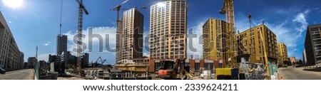 A wonderful construction site, with gold-colored tower houses. A new block is under construction. The picture shows a versatile view of a large construction site and construction workers and cars. 
