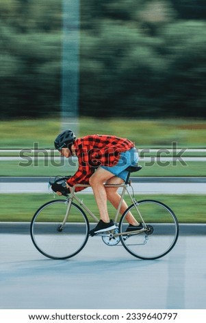 a guy with a bicycle helmet on his head in a red shirt rides an old sports bike photo in motion