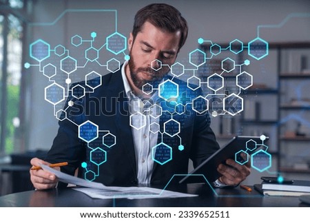 Considered businessman in formal wear signing contract holding tablet device at office room with papers. Concept of successful business deal, agreement, partnership, documents. BLockchain icons.