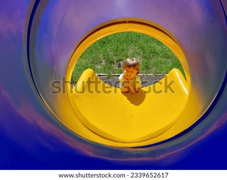 Kid playing on a playground slide, chute, slipstream Royalty-Free Stock Photo #2339652617