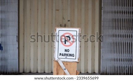 a sign with a forbidden parking symbol and the inscription no parking in front of the shop door