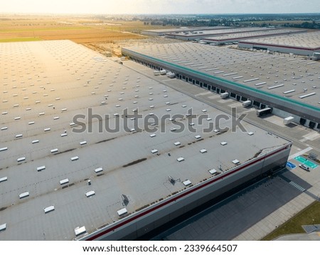 aerial drone view of  warehouse building with bays and trucks in distribution center 
