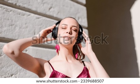 Smiling relaxed woman listening to music with headphones and breathing fresh air.