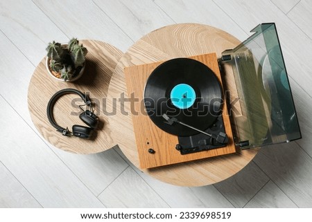 Stylish turntable with vinyl record, headphones and cactus on wooden table indoors, top view Royalty-Free Stock Photo #2339698519