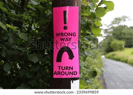 A bright pink temporary sign telling cyclists entered into an event that they need to turn around.