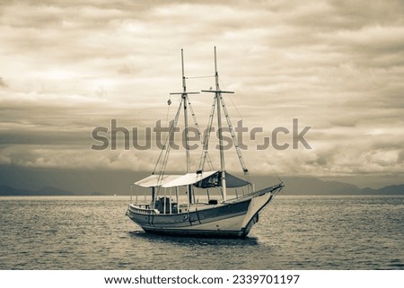 Black and white picture of a ship sailing speed boats and yachts at Praia de Palmas beach Ilha Grande Angra dos Reis Rio de Janeiro Brazil.