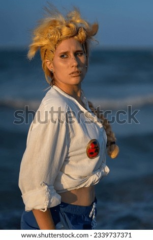 Italian girl cosplay Giorno Giovanna from the anime jojo. Blond woman with blue eyes. Close up to the sea and greenery.