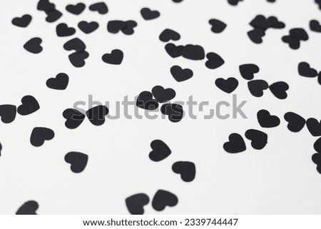 black heart shaped confetti on a white paper background