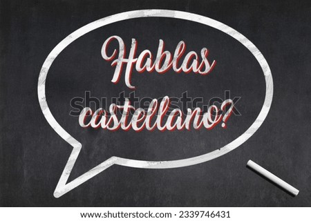 Blackboard with a bubble drawn in the middle with the short phrase in Castilian "Hablas castellano?", meaning "Do you speak Castilian?".