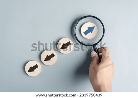 Hand holding Blue arrow and different direction facing opposite direction with black arrow for business disruption and technology transformation and different thinking idea concept Royalty-Free Stock Photo #2339750439