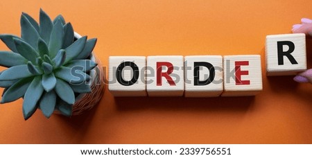 Order symbol. Wooden cubes with word Order. Businessman hand. Beautiful orange background with succulent plant. Business and Order concept. Copy space. Concept word