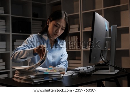 Young adorable Asian businesswoman working with work document during the night, working overtime at night. Royalty-Free Stock Photo #2339760309