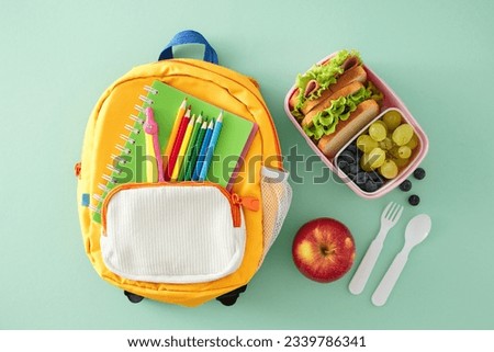 Wholesome snack idea for educational settings. Top view photo of lunchbox, apple, cutlery, compass, pencils, notebook, rucksack on turquoise background with empty space for advert or text Royalty-Free Stock Photo #2339786341