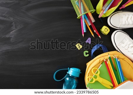 School vibes concept. Top view photo of educational tools, white gumshoes, backpack, water bottle on blackboard background with empty space for promo or message