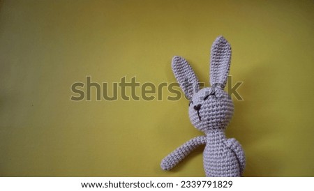 Bunny. Rabbit amigurumi isolated on a yellow background. Needlework concept. Copy space. Easter crochet concept.