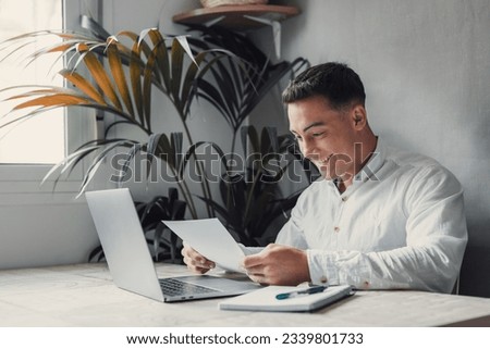 Excited business man student reading postal mail letter overjoyed by great news, happy male winner holding paper bill with loan approval celebrate taxes refund receive salary rise payment sit at desk Royalty-Free Stock Photo #2339801733