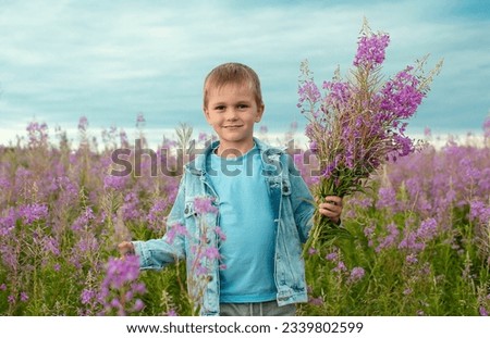 Charming smiling boy with bouquet of wildflowers in field, holding bouquet in front of him. Summer holidays. Spring allergy season. Childhood