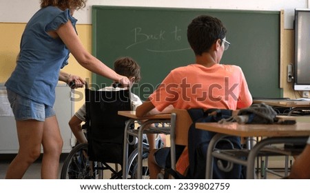 A teacher assists a disabled student with a wheelchair. Back to school concept