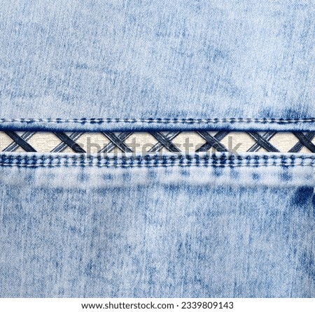 Blue denim background with a seam. Light blue color denim jeans fabric texture. Copy space for text