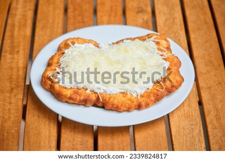 Typical homemade Hungarian food called Langos (in Hungarian Lángos). Deep fried flatbread usually with sour cream, cheese, and garlic.                               Royalty-Free Stock Photo #2339824817