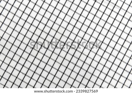 Texture of black and white fabric in a cage. Checkered material. Textile with intersecting white and black lines