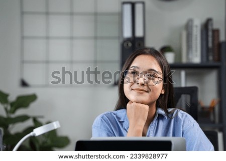beautiful asian female employee Happy woman smiling while working on laptop in office Young woman wearing headphones working online or studying and learning while using notebook. Freelance work Royalty-Free Stock Photo #2339828977