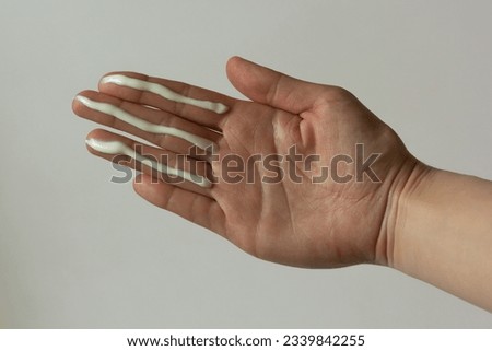 A person applying the correct amount of sunscreen for face and neck - three fingers. Royalty-Free Stock Photo #2339842255