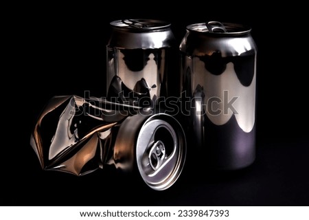 Three aluminum cans for beverage. Low-key picture of some metallic containers taken in studio with dark background.
