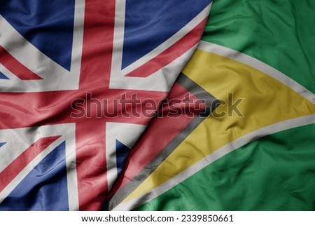 big waving national colorful flag of great britain and national flag of guyana . macro