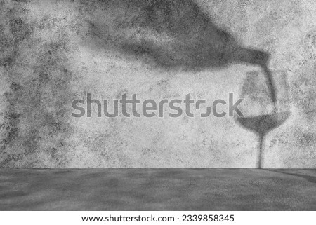Abstract silhouette shadows pouring from a bottle of wine into a glass, gray concrete background. Mockup for product presentation.