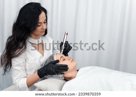 cosmetologist making mesotherapy injection with dermapen on face for rejuvenation. Anti-aging treatment and face lift in cosmetology clinic. medical procedure with Electric pen. banner with copy space Royalty-Free Stock Photo #2339870359