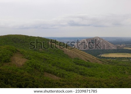 The green peak of a low mountain, overgrown with forest, next to which you can see another mountain, Shihan. Mixed tree species. Summer, Bashkiria, Russia Royalty-Free Stock Photo #2339871785