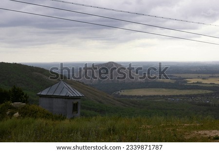 The green peak of a low mountain, overgrown with forest, next to which you can see another mountain, Shihan. abandoned booth next to the old mountain lift. Royalty-Free Stock Photo #2339871787