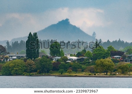 Close-up of houses on shore of Lake Taupo, with mountain in the background, New Zealand Royalty-Free Stock Photo #2339873967