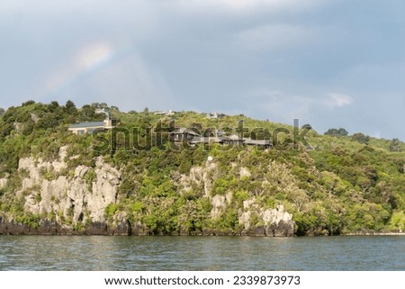Rainbow over Houses in Lake Taupo in New Zealand Royalty-Free Stock Photo #2339873973