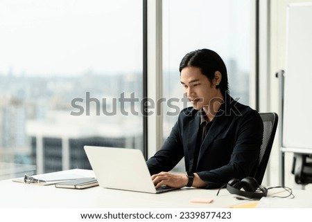 Portrait of handsome asian businessman, successful trader using laptop computer, working online from home. Freelancer copywriter typing on keyboard, planning project sitting at workplace. Technology 